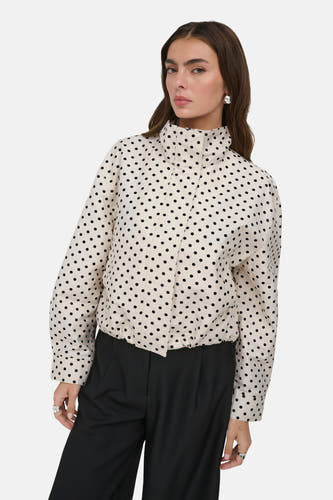 Veste courte blanche ONLY® à pois noirs, col montant et ourlet élastique, portée par un mannequin.