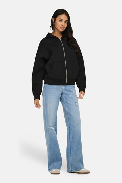 Witte sweater (gilet) van ONLY® met lange rits, kap, zakken en gedragen met een blauwe jeans.