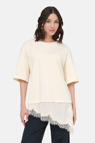 Beige T-shirt met korte mouwen van JDY, met kanten details aan de onderkant en gedragen met een donkere broek.
