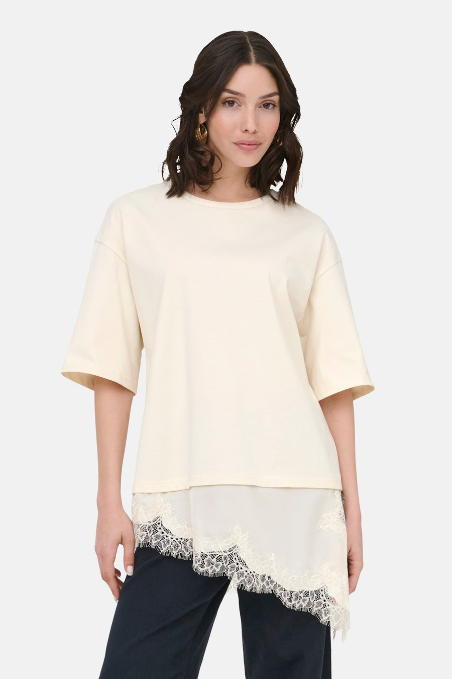 Beige T-shirt met korte mouwen van JDY, met kanten details aan de onderkant en gedragen met een donkere broek.
