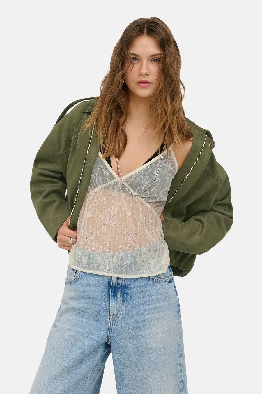 Ecru kanten mouwloze blouse van ONLY®, gedragen met een open groen suède-look jack en een lichte jeans.