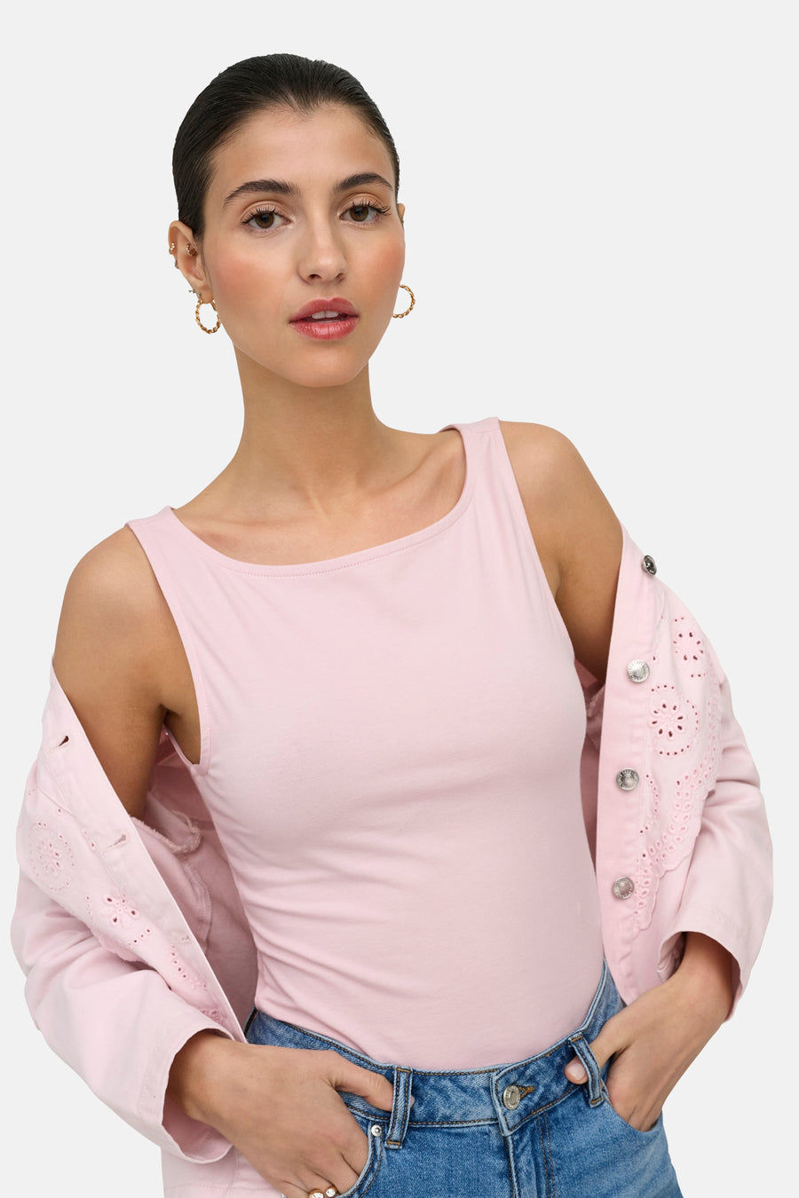 Haut rose sans manches ONLY® à col rond, porté sous une veste brodée rose clair et un jean bleu.