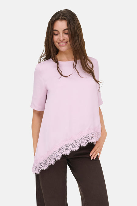 T-shirt à manches courtes rose de JDY, avec ourlet asymétrique et finition en dentelle rose, combiné avec un pantalon marron foncé.
