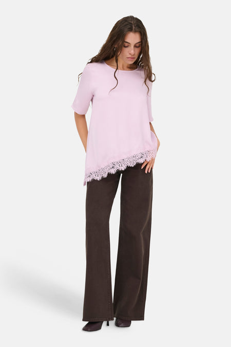 Roze T-shirt met korte mouwen van JDY, met asymmetrische zoom en roze kantafwerking, gecombineerd met een donkerbruine broek.
