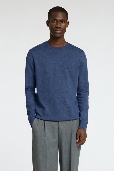 Blauwe trui met ronde hals van SELECTED, gecombineerd met grijze pantalon, staand tegen een witte achtergrond.
