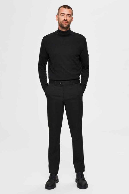 Zwarte coltrui van SELECTED, gladde stof, gedragen door een man met zwarte broek.
