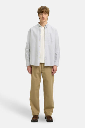 Chemise rayée blanche et noire à longues manches de SELECTED, portée sur un T-shirt crème et un pantalon kaki.