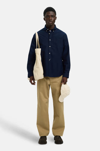 Chemise bleue à manches longues de SELECTED, portée avec un sac en toile et un pantalon kaki.
