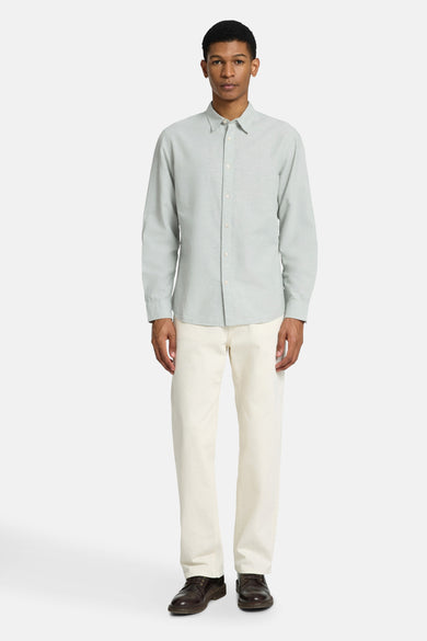 Groen hemd met lange mouwen van SELECTED, met knoopsluiting en gedragen met witte broek en bruine schoenen.
