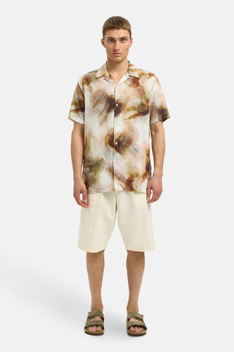 Bruin overhemd met korte mouwen van SELECTED, met een abstract penseelstrekenpatroon, gedragen met crèmekleurige shorts en sandalen.
