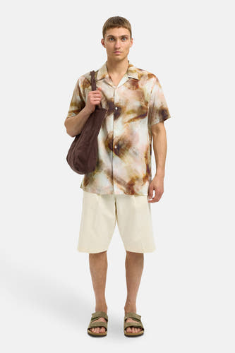 Bruin overhemd met korte mouwen van SELECTED, met een abstract aquarelpatroon, gedragen met ecru shorts en kaki sandalen.
