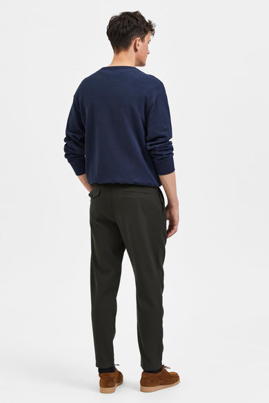 Groene broek van SELECTED, gezien van achteren, gecombineerd met een marineblauwe sweater en bruine suède schoenen.

