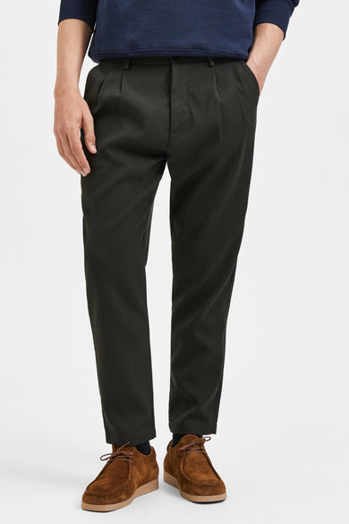 Groene broek van SELECTED, met plooien en bruine schoenen.
