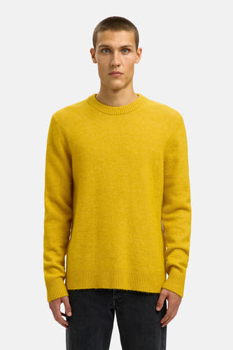 Sweat-shirt gris avec col rond de SELECTED, porté avec un jeans foncé et des bottes en cuir noires.