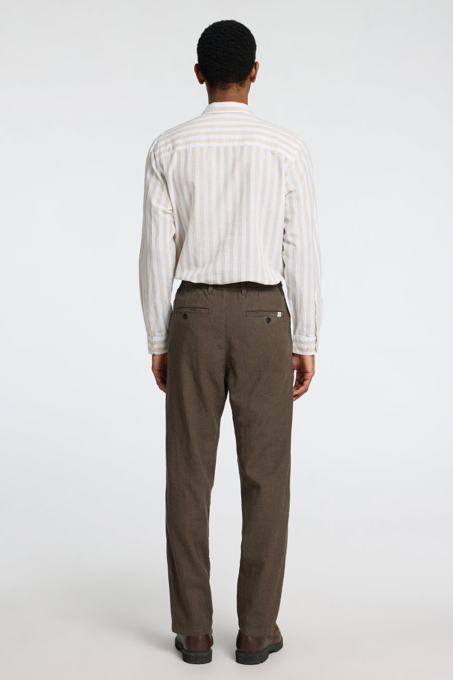 Pantalon kaki de SELECTED, vu de l'arrière, avec une subtile texture et associé à un chemisier rayé.