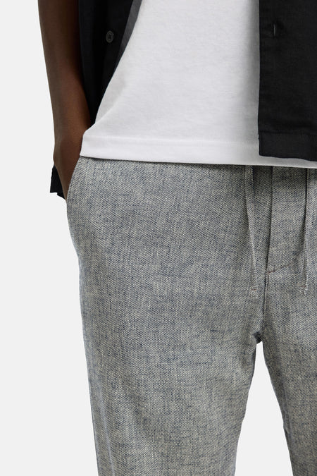 Blauwe broek van SELECTED, met een gemêleerd dessin en een lichte textuur, gedragen met een wit T-shirt.
