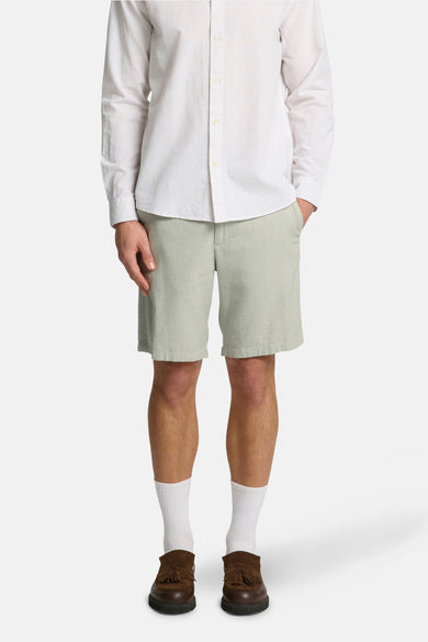 Groene short van SELECTED, gecombineerd met een gestreept overhemd, witte sokken en bruine loafers.
