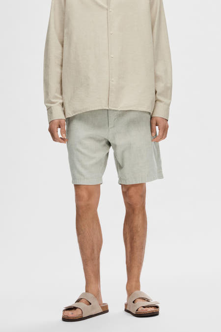 Groene short van SELECTED, gedragen met een beige linnen overhemd en suède sandalen.