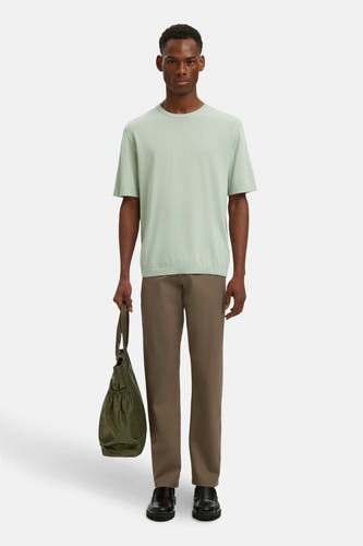 Bruine kostuumbroek van SELECTED, gedragen met een lichtgroen T-shirt, een groene tas en zwarte schoenen.
