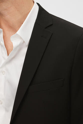 Zwarte blazer van SELECTED, met een revers en borstzak, gedragen over een wit overhemd.
