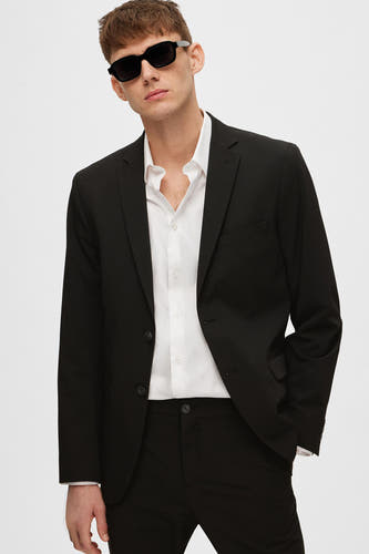 Zwarte blazer van SELECTED, gedragen met een wit overhemd en een zwarte broek.