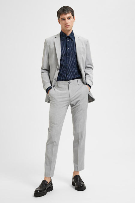 Grijze kostuumbroek van SELECTED, gecombineerd met een blauw overhemd met stippen en zwarte loafers.
