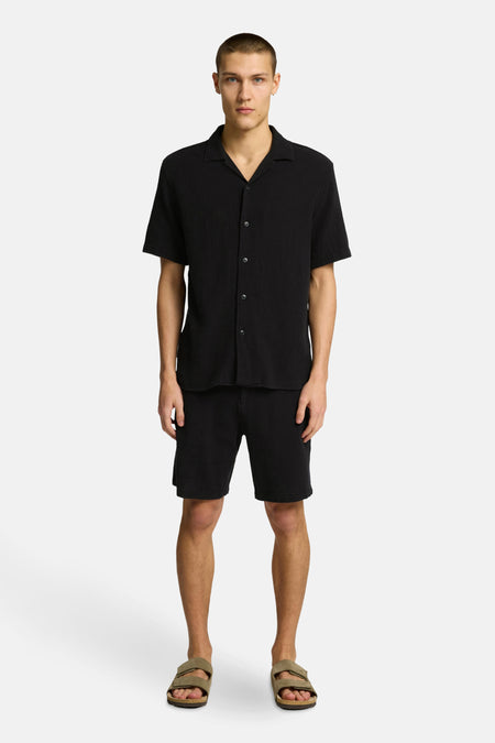 Short noir de SELECTED, associé à un t-shirt noir et des sandales.