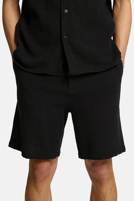 Short noir de SELECTED, avec une finition texturée, porté avec un t-shirt coordonné.