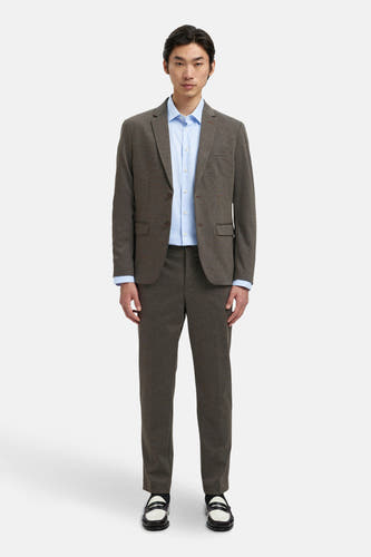 Bruine blazer van SELECTED, gedragen over een lichtblauw overhemd, met bijpassende broek en zwart-witte schoenen.
