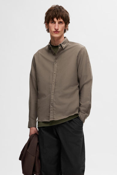 Bruin overhemd met lange mouwen van SELECTED, gedragen over een groen T-shirt, met zwarte broek.