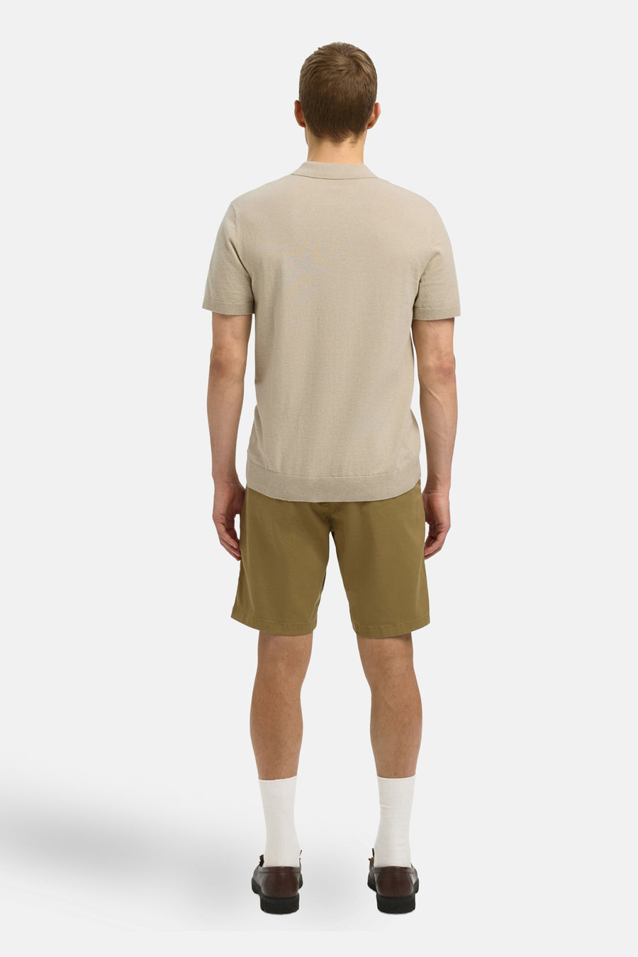 Beige polo met korte mouwen van SELECTED, gezien vanaf de achterkant, gecombineerd met khaki shorts, witte sokken en bruine loafers.
