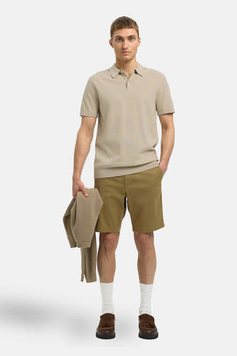 Beige polo met korte mouwen van SELECTED, gedragen met kaki shorts, witte sokken en bruine loafers.
