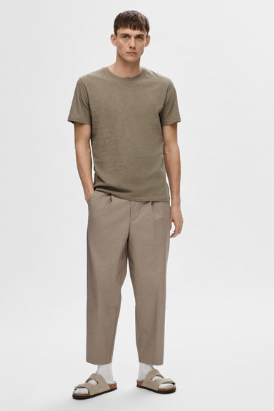 Beige broek van SELECTED, met plooien, gedragen met een olijfgroen T-shirt en suède sandalen met witte sokken.