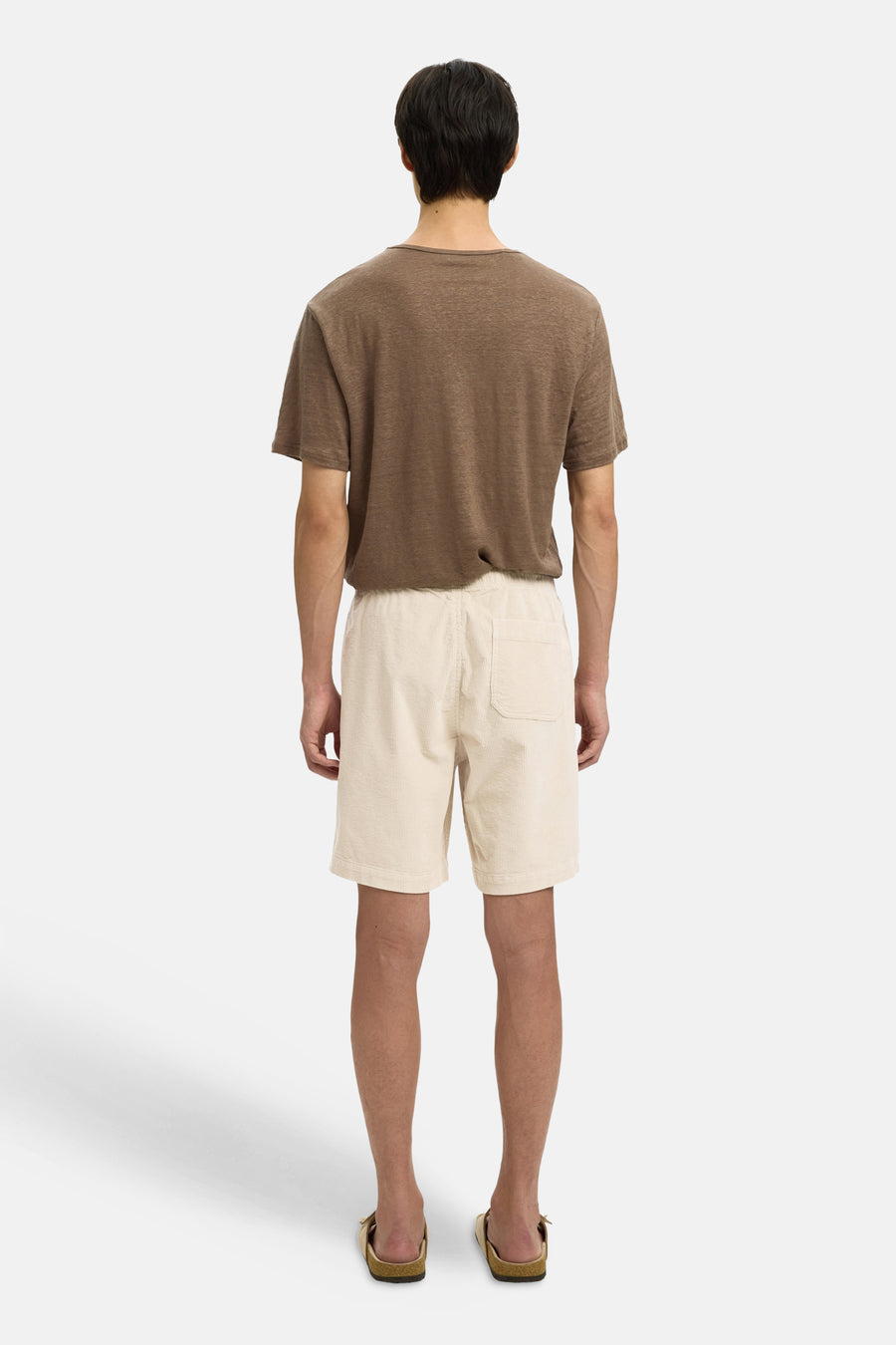 Short écru de SELECTED, avec une poche arrière et une taille élastique, porté avec un t-shirt marron et des sandales.