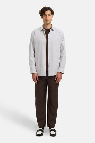 Chemise blanche (manches longues) de SELECTED, avec des rayures verticales subtiles, portée sur une chemise brune et un pantalon brun.