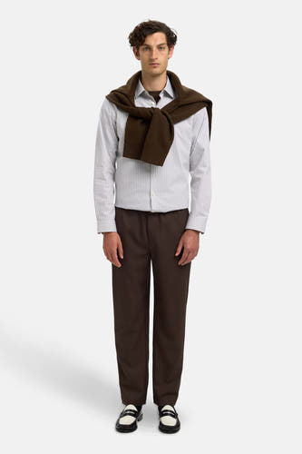 Chemise blanche à manches longues de SELECTED, rayée et stylée avec une veste brune sur les épaules.