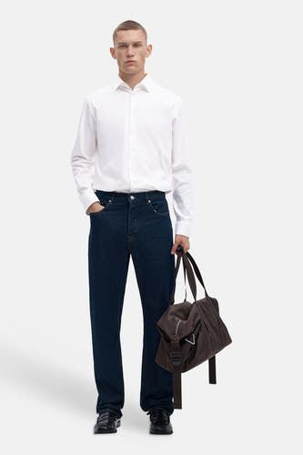 Wit overhemd met lange mouwen van SELECTED, gestreken stof, klassieke knoopsluiting, model in lifestyle pose met donkerblauwe jeans en bruine tas