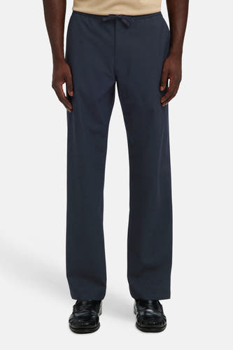 Donkerblauwe broek met elastische taille van SELECTED, rechte pasvorm, voorzien van trekkoord, gedragen met beige trui en zwarte loafers, front view.