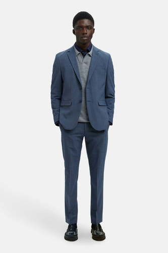 Blazer bleu de SELECTED, porté avec une chemise grise et un gilet bleu marine, associé à des chaussures noires.