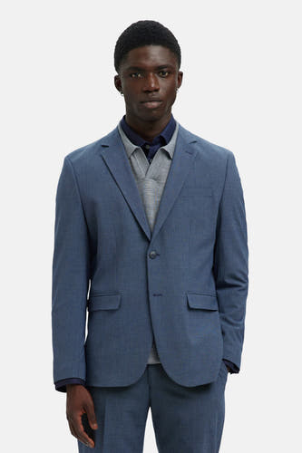 Blazer bleu de SELECTED, avec une fine texture tissée et porté sur un gilet gris et un chemisier bleu marine.