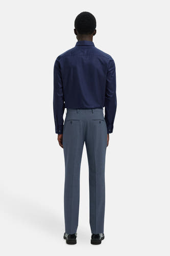 Blauwe kostuumbroek van SELECTED, met achterzakken, gecombineerd met een donkerblauw overhemd en zwarte schoenen.
