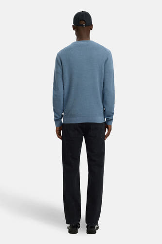 Blauwe trui met ronde hals van SELECTED, met een fijn gebreide textuur en gecombineerd met een zwarte jeans en pet.
