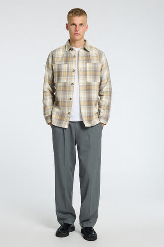 Beige hemd met lange mouwen van SELECTED, met ruitpatroon, gedragen over een wit t-shirt en grijze pantalon.
