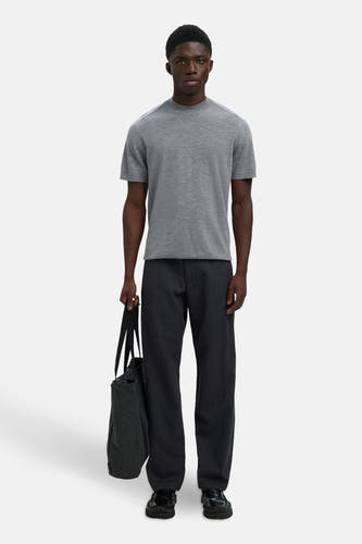 Grijze trui van SELECTED, met korte mouwen, gecombineerd met donkere broek en zwarte tote bag.