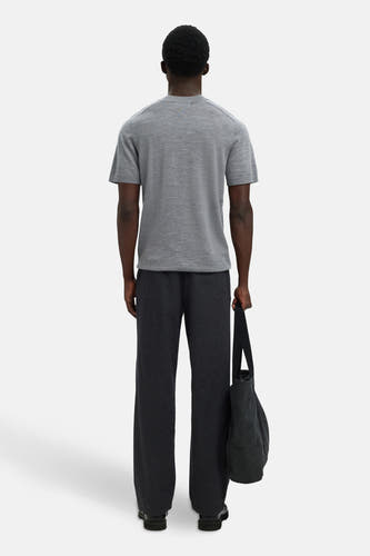 Grijze trui van SELECTED, gezien van achteren, met donkere pantalon en een zwarte tas.
