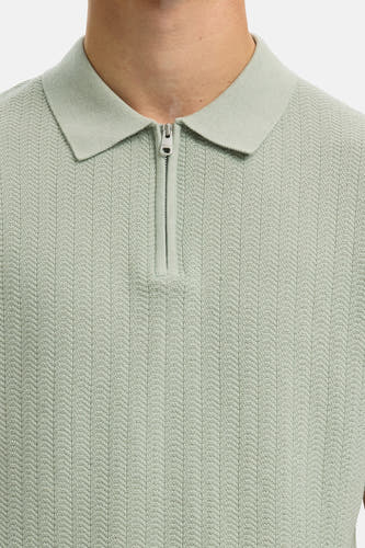 Polo verte de SELECTED, avec une fermeture éclair courte et une subtile structure à chevrons.