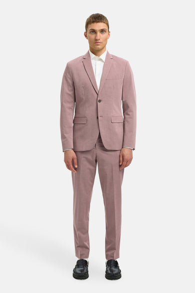 Man in roze pak met witte blouse en zwarte loafers.