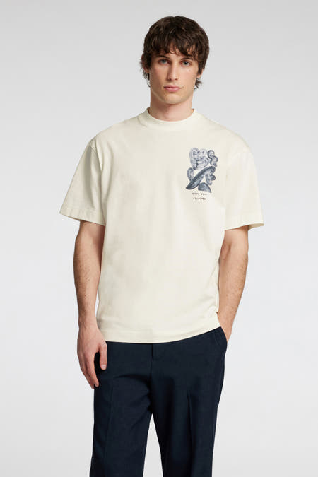 Ecru T-shirt met korte mouwen van SELECTED, met grafische print op de borst, gecombineerd met donkerblauwe pantalon.
