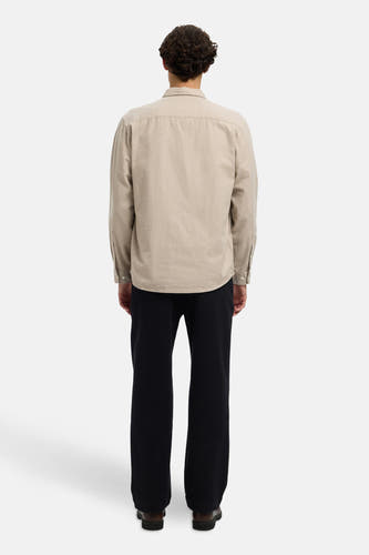 Beige hemd met lange mouwen van SELECTED, met knoopsluiting en gedragen met zwarte pantalon en bruine schoenen.
