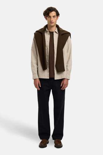 Beige overhemd met lange mouwen van SELECTED, met een bruine trui nonchalant over de schouders en zwarte pantalon.
